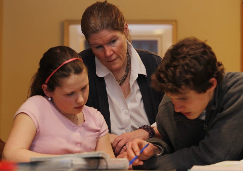 Ellen Purtell, center, watches her 15-year-old son Bobby Costanzo, right, help his sister Grace Costanzo, 10, with homework. (Julio Cortez/AP)
