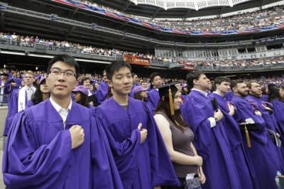 New York University graduates stand during the playing of the national anthem before their graduation ceremony Wednesday, May 21, 2014, at Yankee Stadium in New York. (AP)