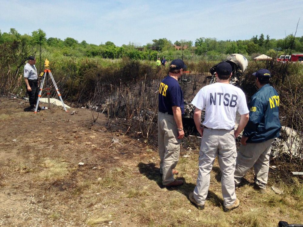 NTSB investigators on Sunday are at the scene of a private plane that plunged down an embankment and erupted in flames during a takeoff attempt Saturday night at Hanscom Field in Bedford. (National Transportation Safety Board/AP)