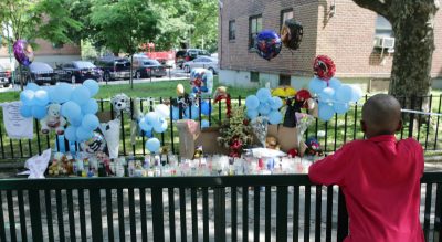 A boy looks at a memorial outside the Boulevard Houses after a news conference there in the borough of Brooklyn in New York on Wednesday, June 4, 2014. On Sunday, June, 1, two children were stabbed at at the housing complex. (Peter Morgan/AP)