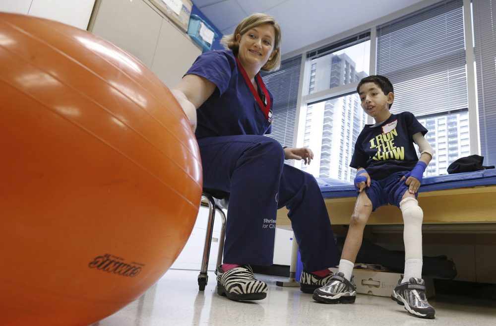 Therapist Katherine Hartigan works with Ihor Lakatosh last month at Shriners Hospital for Children in Boston. Ihor had been burned in Ukraine, where his mother abandoned him at a hospital in 2011. (Michael Dwyer/AP)