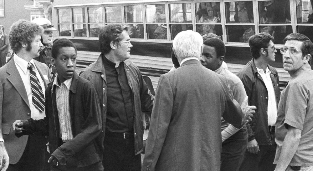 Two African American students walk through line of officials as they left bus to attend the predominantly white South Boston High in South Boston on Thursday, Sept. 12, 1974. It was the first day of a court-ordered busing program to integrate Boston public schools. (AP)