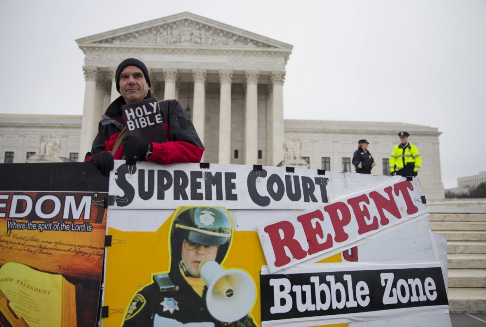 The High Court's ruling against a Massachusetts buffer zone law on June 26, 2014 doesn't take away a woman's constitutional right to unfettered reproductive healthcare, including abortion.

Pictured: A protester of the buffer zone law stood outside the Supreme Court on Wednesday, January 2014, when the Court heard arguments on the regulation of protests outside abortion clinics. (Evan Vucci/AP)