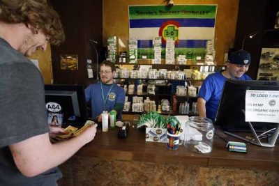 A customer pays cash for retail marijuana at 3D Cannabis Center, in Denver, Thursday, May 8, 2014. (AP)