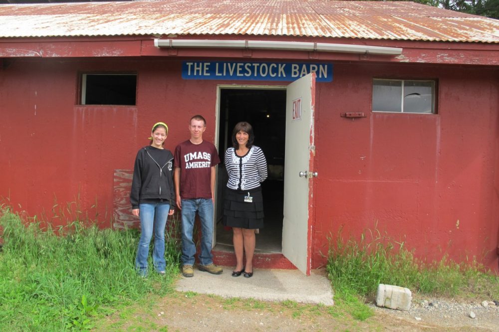 Aggie seniors Jenna Illingworth and Austin Broderick stand with Aggie Principal Tammy Quinn in front of the livestock barn in Walpole, Mass. (Anthony Brooks/WBUR)