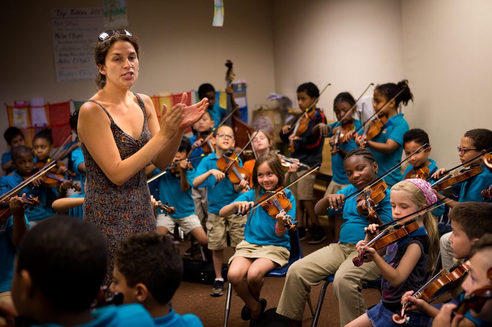 Kathleen Jara, co-director of the El Sistema program at the Conservatory Lab Charter School in Boston, directs orchestra students during a rehearsal. (Jesse Costa/WBUR)