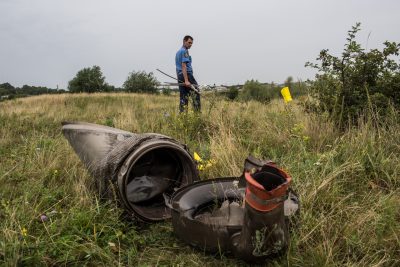 A Ukrainian police officer searches for human remains from Malaysia Airlines Flight 17 found in a field on July 18 in Grabovka, Ukraine. (Brendan Hoffman/Getty Images)