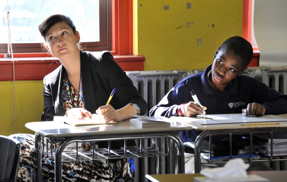 Tracy Taylor, assistant head teacher with Kingsford Community School of London watches a sixth grade math lesson beside student Dema'd McCray, 12, at the Brooke Roslindale Charter School in Boston. (Josh Reynolds/AP)