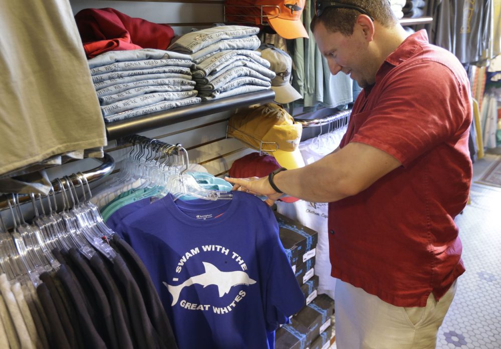 Vacationer Mark McCurdy, of Everett, examines shark-themed clothing at the Chatham Clothing Bar in Chatham, Mass. Growing sightings of great white sharks off Cape Cod are generating business for local entrepreneurs as residents and tourists seek a glimpse of the offshore predators -- or purchase their shark-themed memorabilia and apparel. (Steven Senne/AP)