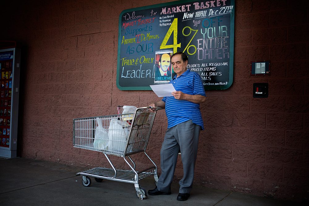 A shopper at the Somerville Market Basket reads a sheet of paper calling for people not to shop at the Market Basket store until Arthur T. Demoulas is reinstated as CEO. (Jesse Costa/WBUR)