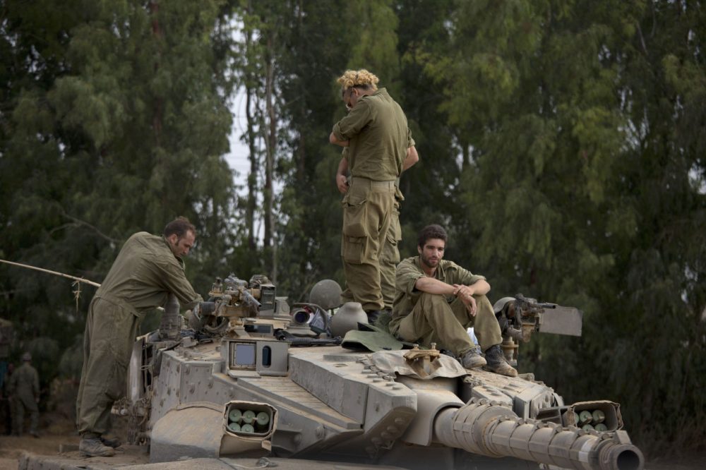Israeli soldiers work on a tank near the Israel and Gaza border Thursday, July 24, 2014. Israeli tanks and warplanes bombarded the Gaza Strip on Thursday, as Hamas militants stuck to their demand for the lifting of an Israeli and Egyptian blockade in the face of U.S. efforts to reach a cease-fire. (Dusan Vranic/AP)
