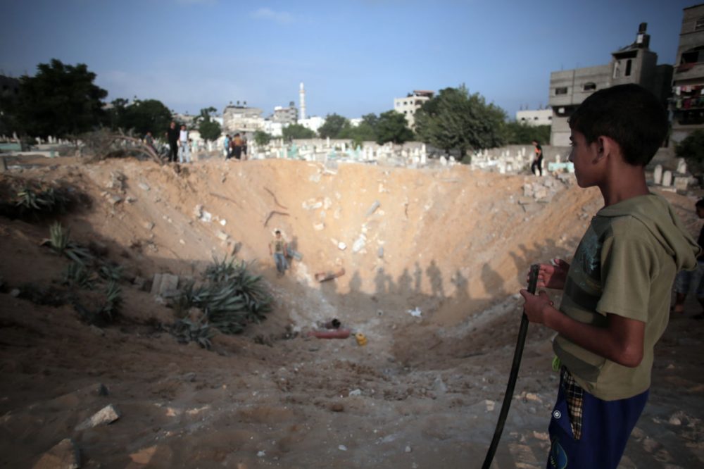 Palestinians check a crater caused by an Israeli strike at a cemetery in the Jabaliya refugee camp, northern Gaza Strip, on Monday. (Khalil Hamra/AP)