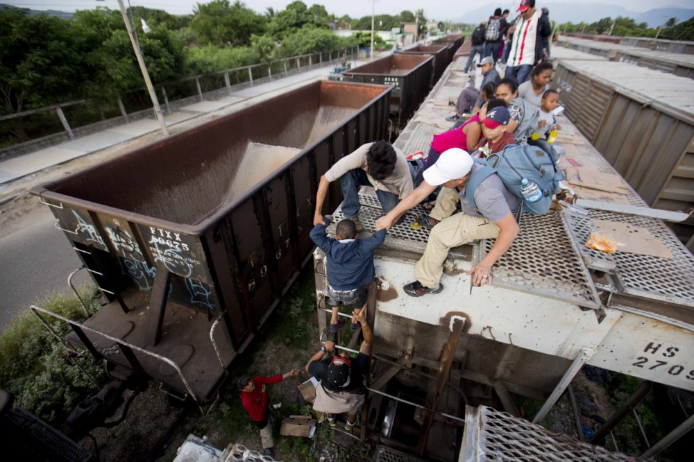 A young boy is is helped down from the top of a freight car, as Central Americans board a northbound freight train in Ixtepec, Mexico. (Eduardo Verdugo/AP)