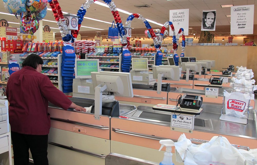 Signs in support of ousted CEO Arthur T. Demoulas hang above empty checkout lines at a Market Basket in Somerville on Tuesday. (Curt Nickisch/WBUR)