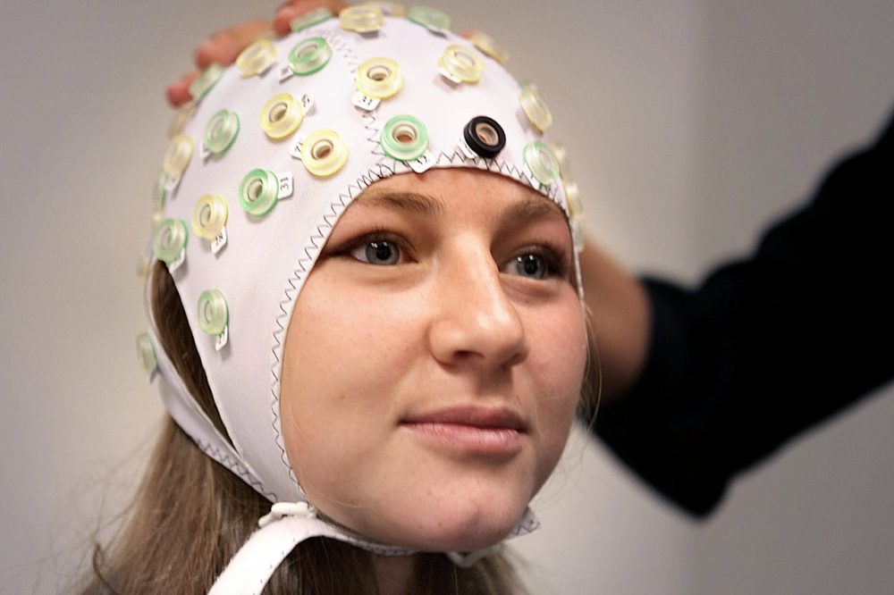 Sarah Beth Spitzer, a research assistant at Harvard University, wears an EEG cap, used to localize the regions of the brain needed to stimulate during the test. (Jesse Costa/WBUR)