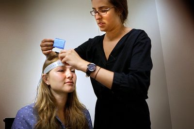 Ann Carroll fits nodes to Sarah Beth Spitzer’s forehead in preparation for transcranial direct current stimulation testing at the Center for Brain Research at Harvard. (Jesse Costa/WBUR)