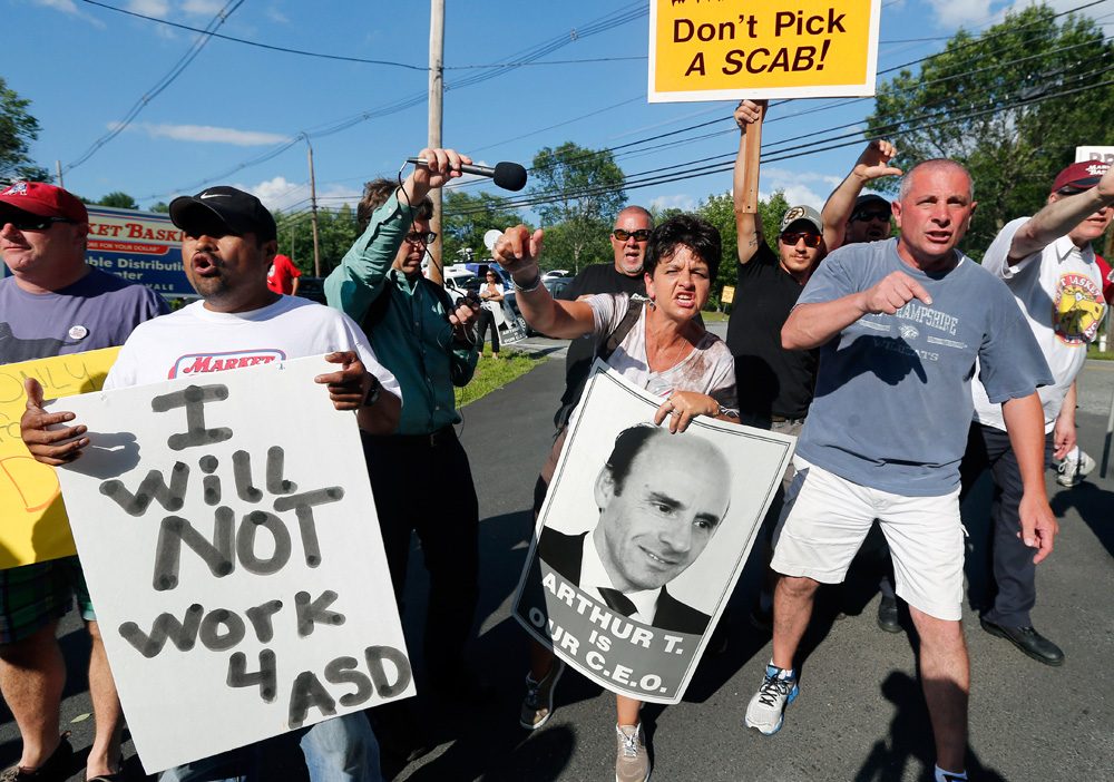 Protesters hold signs and taunt a car leaving the site of a Market Basket job fair in Andover on Wednesday. (Elise Amendola/AP)