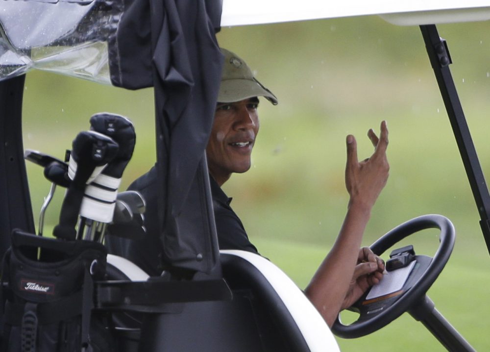President Barack Obama gestures from his golf cart off while golfing at Vineyard Golf Club in Edgartown, August 2013. (Steven Senne/AP)