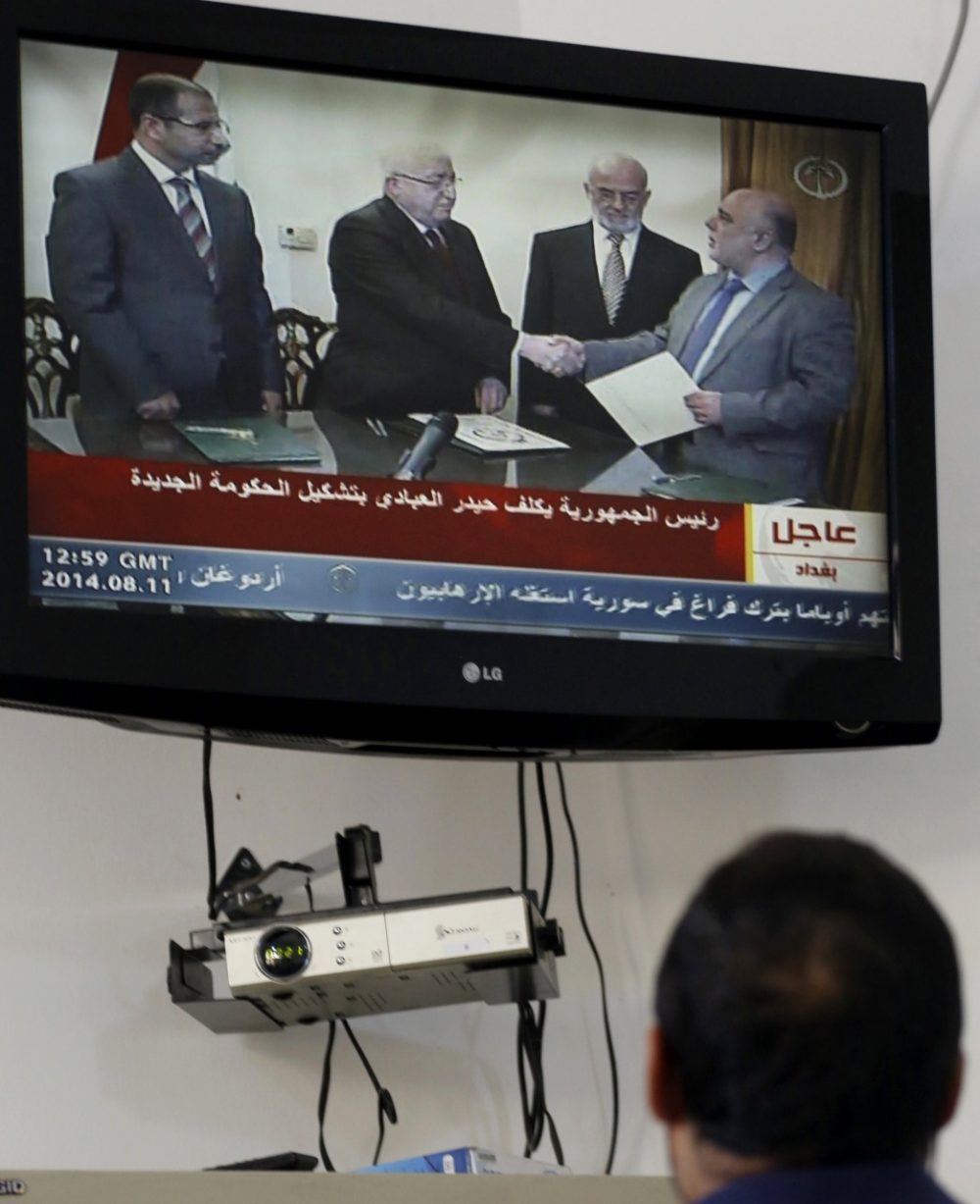 A journalist watches as Iraqi President Fuad Masum shakes hands with deputy parliamentary speaker Haidar al-Abadi, who has been tasked with forming a government, during a brief ceremony broadcast on state television on August 11, 2014, in Baghdad. (Sabah Arar/AFP/Getty Images)