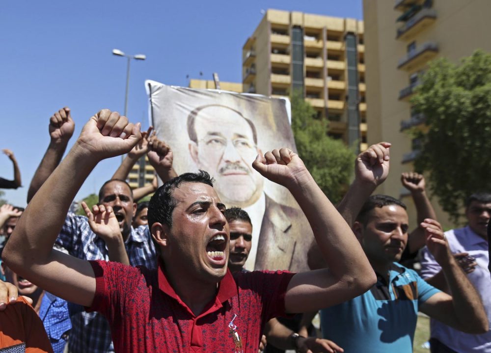 Iraqis chant pro-government slogans and display placards bearing a picture of embattled Prime Minister Nouri al-Maliki during a demonstration in Baghdad on Monday (Hadi Mizban/AP)