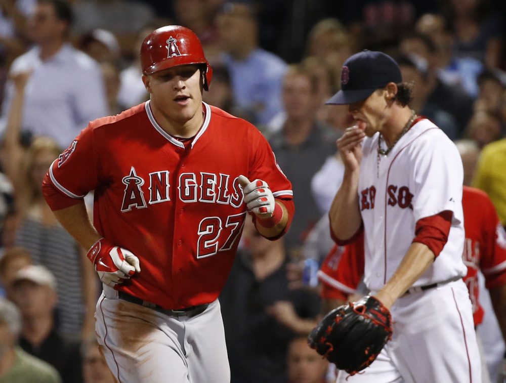 Angels' Mike Trout trots to the dugout after scoring on Josh Hamilton's sacrifice fly as Boston Red Sox starting pitcher Clay Buchholz, right, walks back to the mound. (AP/Elise Amendola)