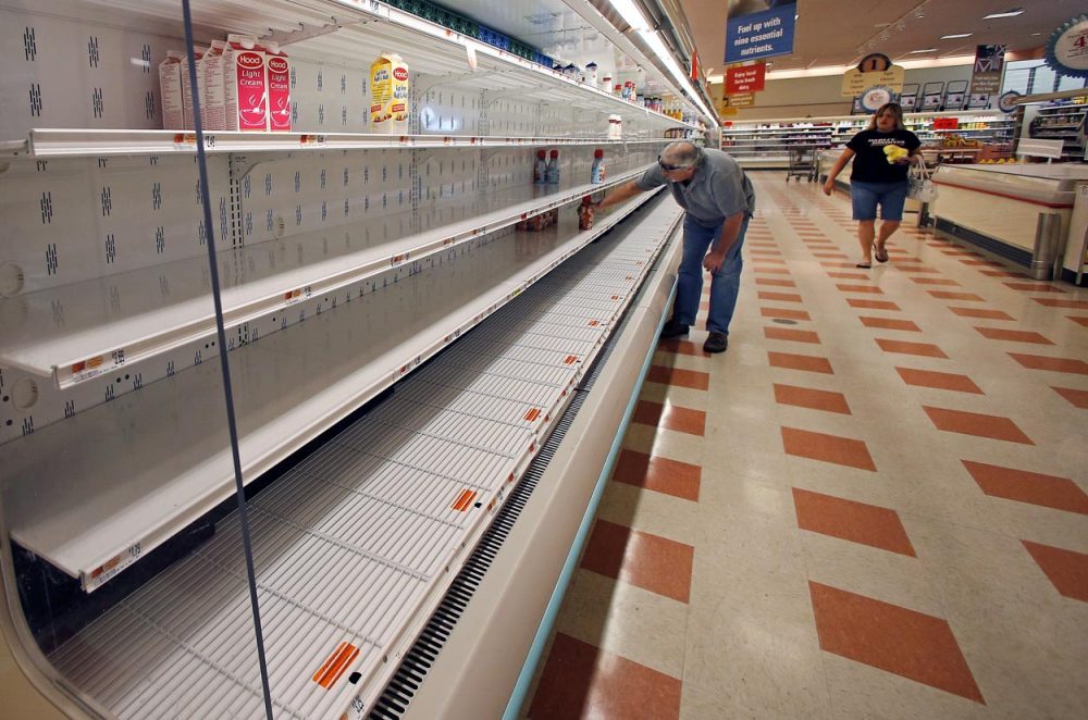 A shopper reaches into a mostly empty dairy shelf at Market Basket in Haverhill on Monday. (Elise Amendola/AP)