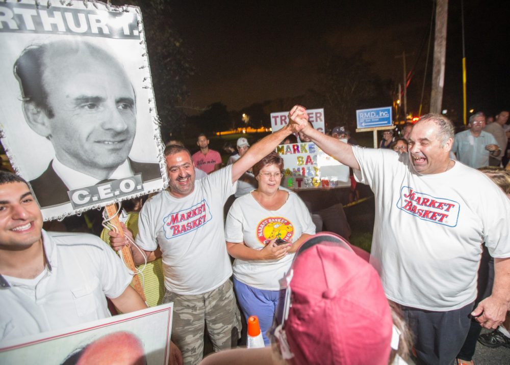 Protesters celebrate outside Market Basket headquarters in Tewksbury last Wednesday night after the grocery chain reached a deal to return control back to Arthur T. Demoulas. (Aram Boghosian for WBUR