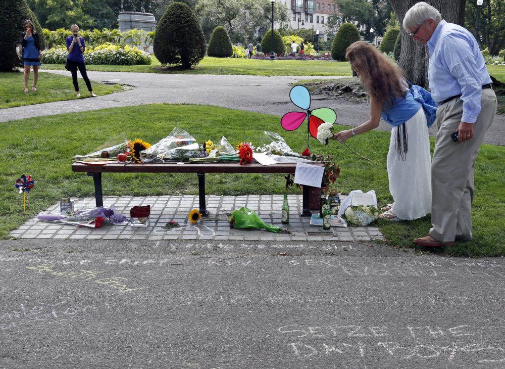Don Makson watches as Suzette Demarais places flowers on a bench at Boston's Public Garden, Tuesday, Aug. 12, 2014, where a small memorial has sprung up at the place where Robin Williams filmed a scene during the movie, &quot;Good Will Hunting.&quot; Williams, 63, died at his San Francisco Bay Area home Monday in an apparent suicide. (AP)
