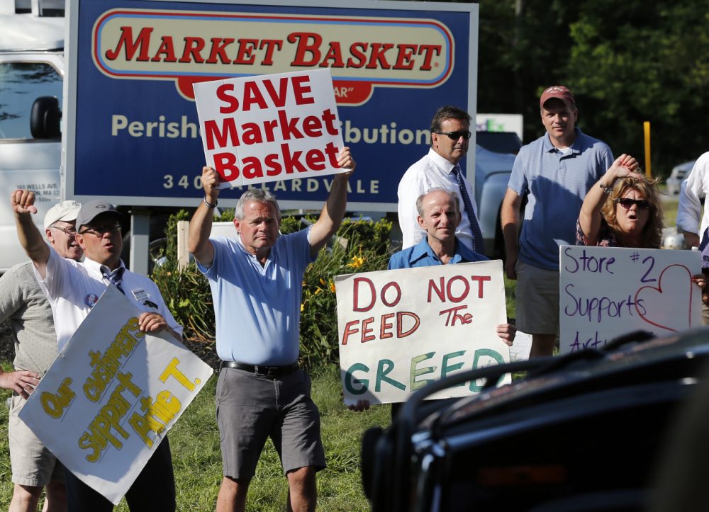 Protesters hold signs and taunt a car entering the site of a Market Basket Supermarket job fair in Andover, Mass., Wednesday, Aug. 6, 2014. Market Basket employees and their supporters are calling for the reinstatement of their fired CEO, even as the company is in the midst of a three-day job fair to replace employees who have refused to work during a revolt that is costing the supermarket chain millions. (AP)