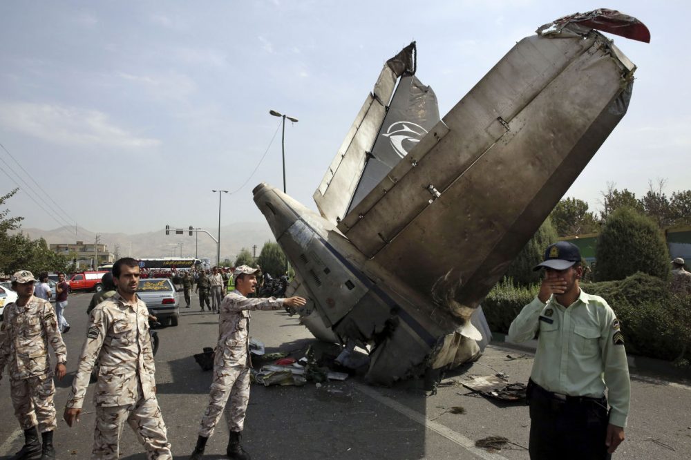 Iranian Revolutionary Guards and police officers inspect the site of a passenger plane crash near the capital Tehran, Iran, Sunday, Aug. 10, 2014. An Iranian passenger plane crashed Sunday while taking off from an airport near the capital, killing tens of people onboard, state media reported. (Vahid Salemi/AP)