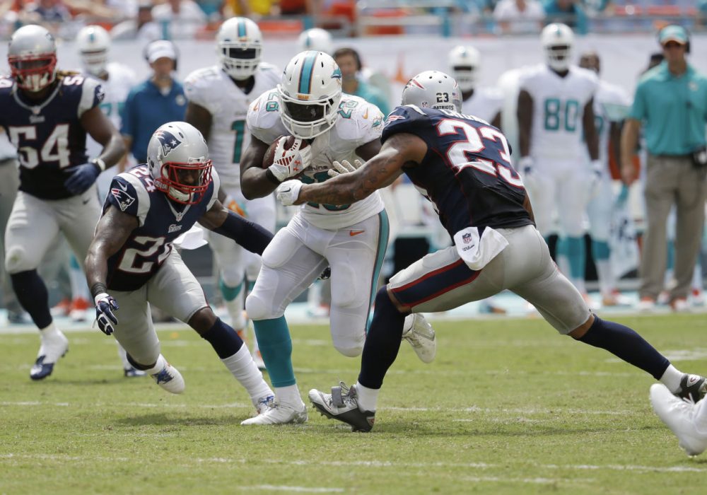 Patriots cornerback Darrelle Revis (24) and  free safety Patrick Chung (23) attempt to tackle Miami Dolphins running back Knowshon Moreno (28) during the second half of an NFL  football game, in Miami Gardens, Fla., Sunday Sept. 7, 2014. (Lynne Sladky/AP)