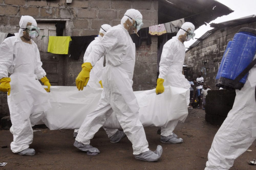Health workers carry the body of a woman they suspect died from the Ebola virus in Monrovia in 2014. (Abbas Dulleh/AP)