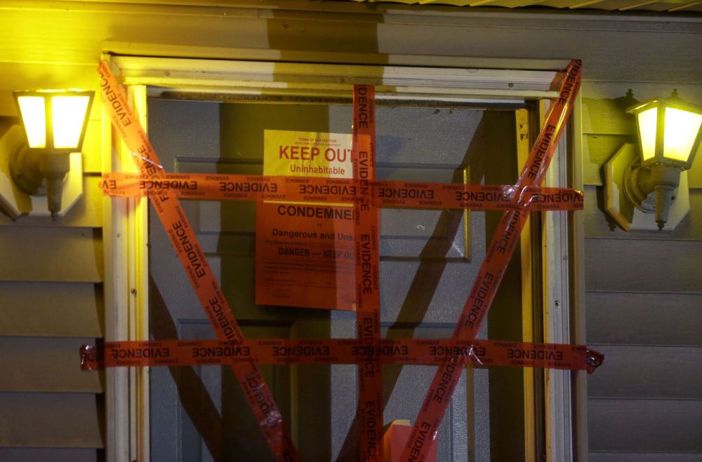 A &quot;condemned&quot; sign is attached behind police tape to the front door of a house where authorities say the bodies of three infants were found Thursday in Blackstone. (Steven Senne/AP)