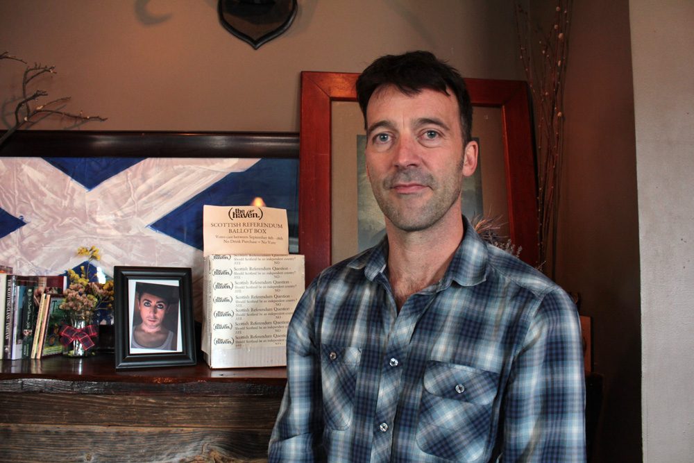 The owner of the Haven, Scotsman Jason Waddleton, in front of the pub's &quot;ballot box&quot; (Shannon Dooling/WBUR)