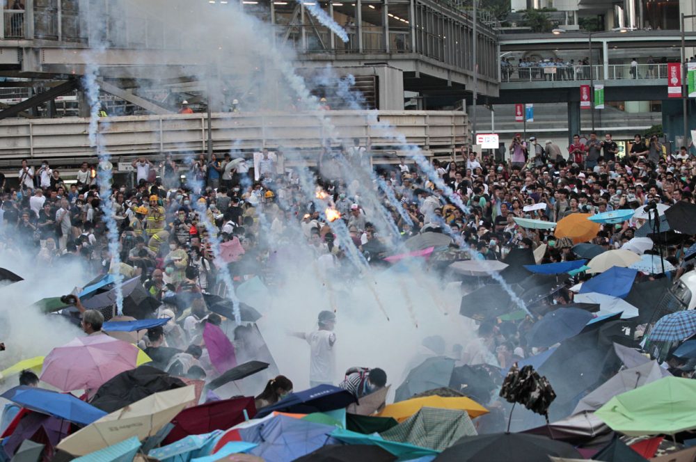 Riot police launch tear gas into the crowd as thousands of protesters surround the government headquarters in Hong Kong Sunday. (Wally Santana/AP)