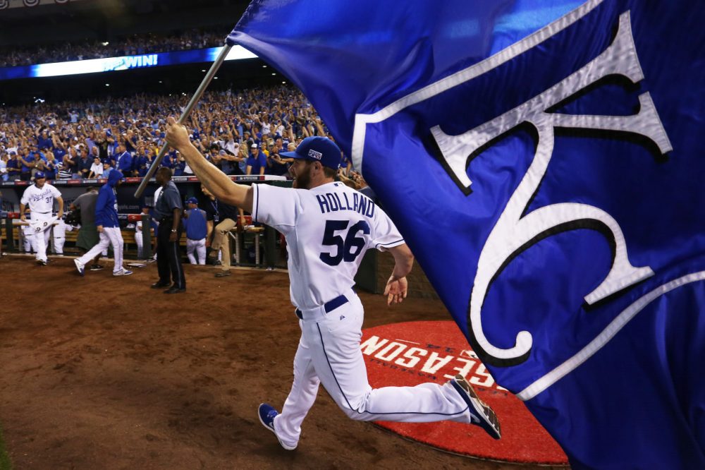 Greg Holland of the Kansas City Royals celebrates with a team flag after they defeated the Oakland Athletics 9 to 8 in the 12th inning of their American League Wild Card game. (Ed Zurga/Getty Images)
