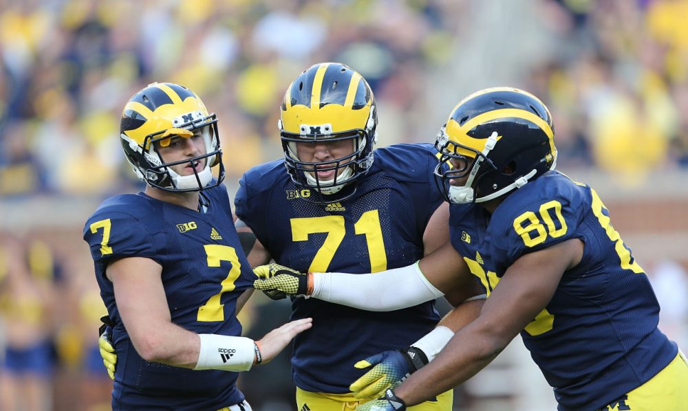After suffering an illegal hit to the head, Michigan quarterback Shane Morris had to be supported by his teammates. But he remained in the game for two more plays (Leon Halip/Getty Images)