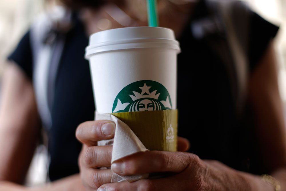 A woman holds a coffee drink outside a Starbucks in Chicago on May 31. (Gene J. Puskar/AP)