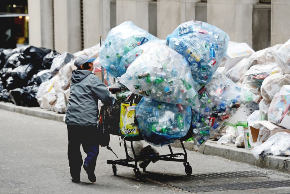 A collector of recyclable bottles and cans that can be redeemed for a cash deposit, takes advantage of the recycling that has piled up on William Street in New York. (Henny Ray Abrams/AP)