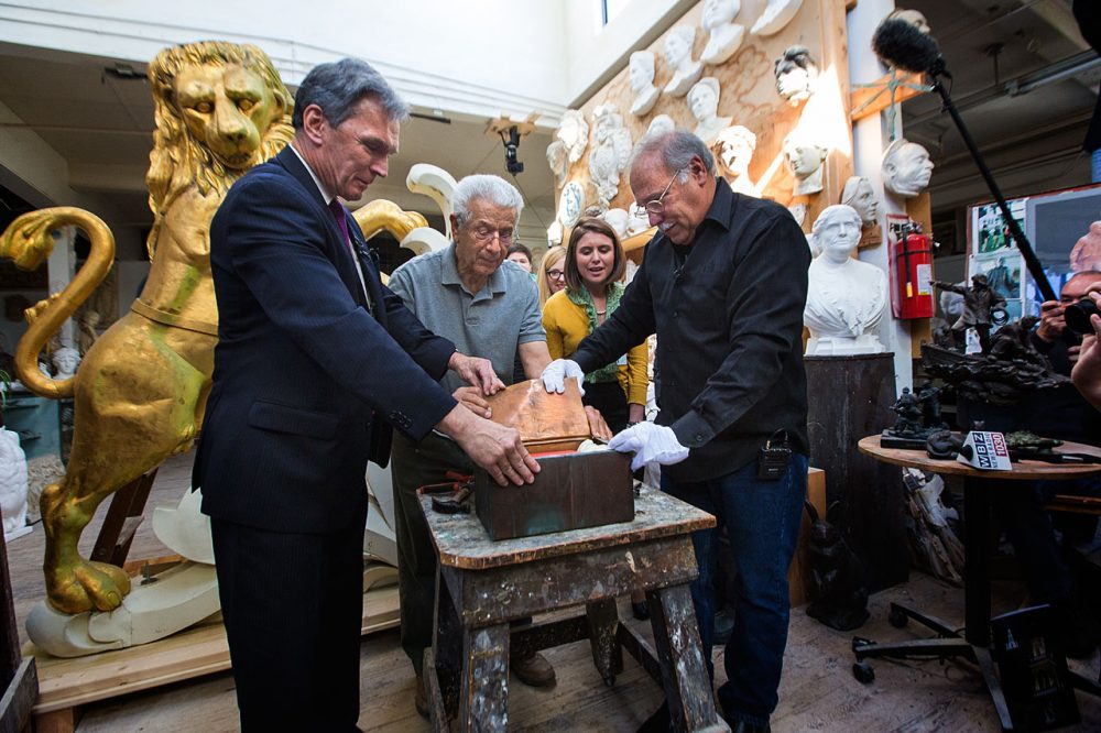 From left to right, Brian LeMay, executive director of the Bostonian Society, restorer George Stratakis, and Bob Shure, owner of Skylight Studios in Woburn, open the copper time capsule that was left in the lion statue on top of the Old State House for more than 100 years. (Jesse Costa/WBUR)