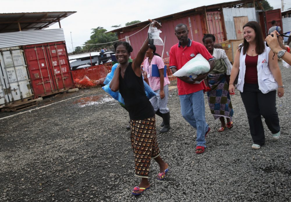 Ebola survivor Sontay Massaley, 37, smiles with Doctors Without Borders (MSF), staff after being released from the MSF treatment center on October 12, 2014 in Paynesville, Liberia. In her hand she held a bag containing her cell phone, which had been disinfected. She said she was there for eight days, after having first arrived sick and tested positive for the disease. (John Moore/Getty Images)