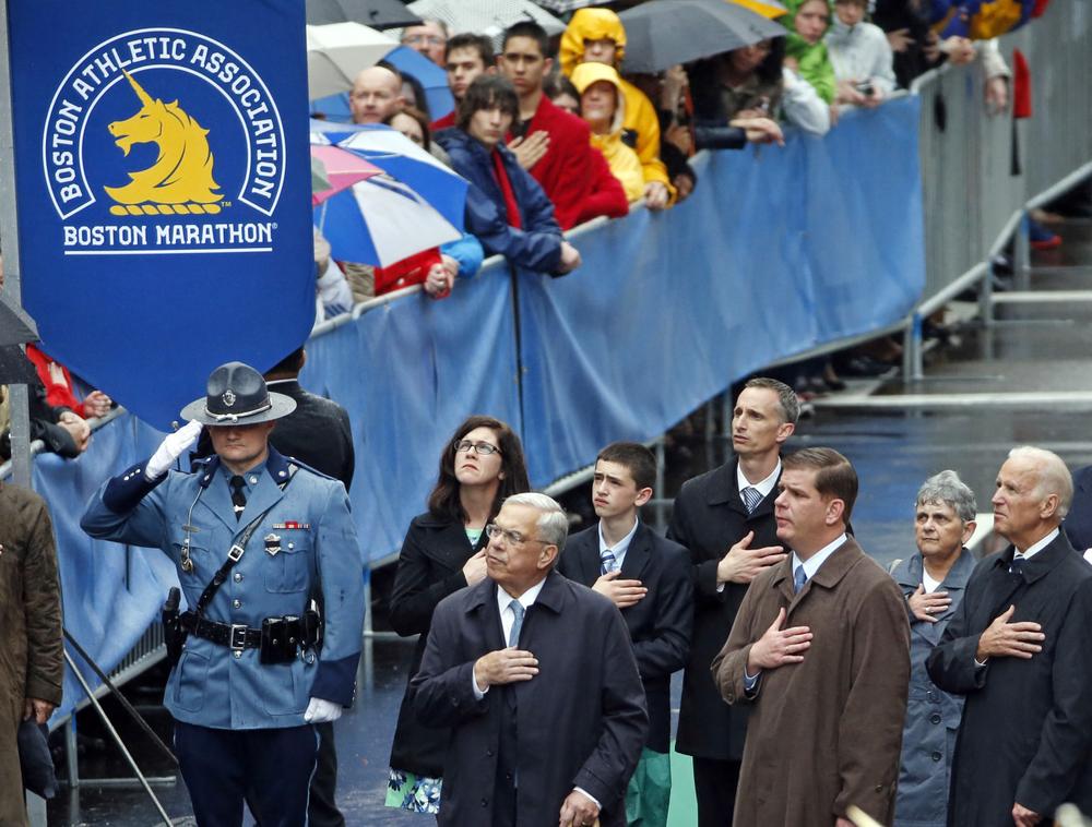 Former Boston Mayor Thomas Menino, center, Boston Mayor Marty Walsh, third from right, and Vice President Joe Biden, right, salute along with the family of Boston Marathon bombing victim Martin Richard, behind, during a remembrance ceremony at the finish line on Boylston Street in Boston, on April 15, 2014. (Elise Amendola/AP)