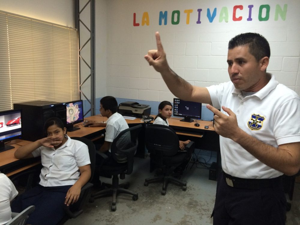 A police officer in Santa Ana, El Salvador teaches a group of sixth graders how to use computers as part of the GREAT program. (Jude Joffe-Block/KJZZ)