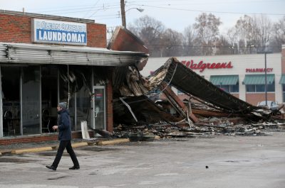 A reporter walks by a building that was damaged during a demonstration on November 25, 2014 in Dellwood, Missouri. Demonstrators caused extensive damage in Ferguson and surrounding areas after a St. Louis County grand jury decided to not indict Ferguson police Officer Darren Wilson in the shooting of Michael Brown. (Justin Sullivan/Getty Images)