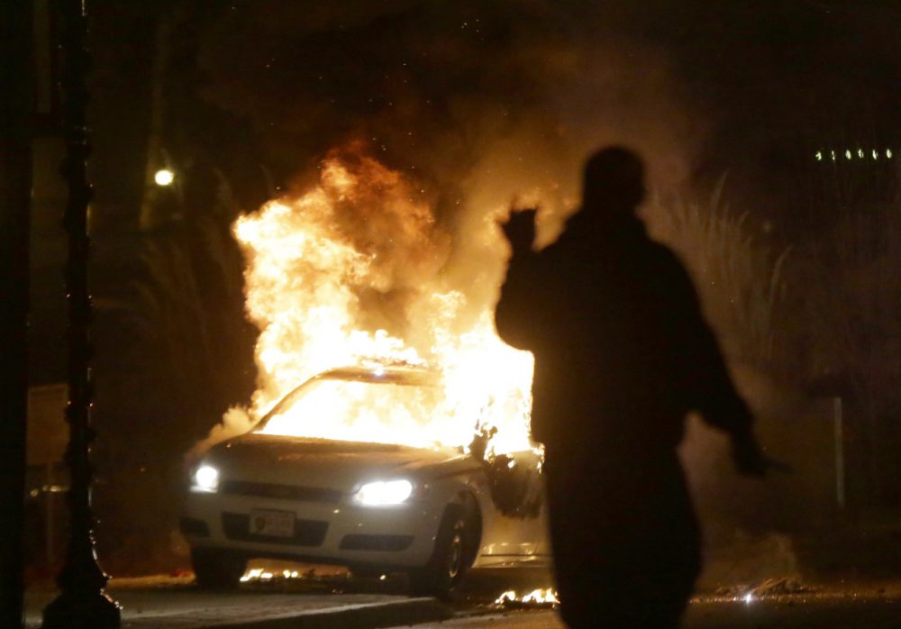 A police car is set on fire after a group of protesters vandalize the vehicle. (Charlie Riedel/AP)