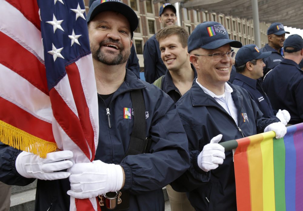 Retired U.S. Air Force Master Sgt. Eric Bullen, of Westborough, Mass., left, holds an American flag as U.S. Army veteran Ian Ryan, of Dennis, Mass., front right, rolls up an OutVets banner after marching with a group representing LGBT military veterans in a Veterans Day parade for the first time in Boston on Tuesday, Nov. 11, 2014. (Steven Senne/AP)