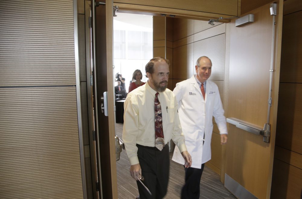 Dr. Rick Sacra, a UMass Medical School faculty member who contracted the Ebola virus in Liberia, walks out of a media availability with Chancellor Michael Collins Sept. 4 in Worcester. (Stephan Savoia/AP)