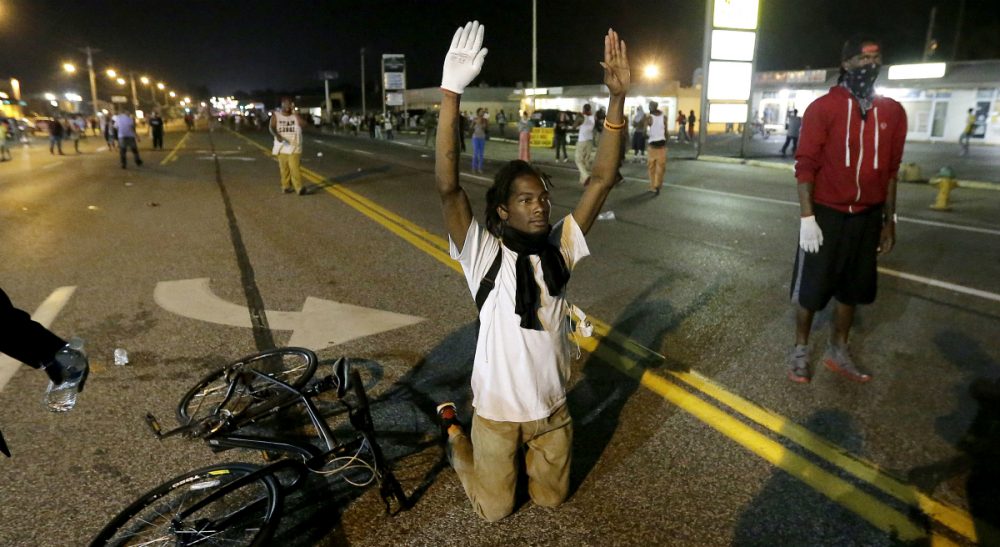 Barbara Beckwith on the challenge of taking action toward a goal that may never be reached. In this photograph, a man holds his hands up in the street after a standoff with police Monday, Aug. 18, 2014, during a protest for Michael Brown, who was killed by a police officer Aug. 9 in Ferguson, Mo. (Charlie Riedel/AP)
