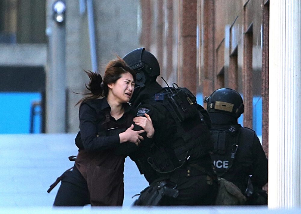 A hostage runs to armed tactical response police officers for safety after she escaped from a cafe under siege at Martin Place in the central business district of Sydney, Australia. (Rob Griffith/AP)