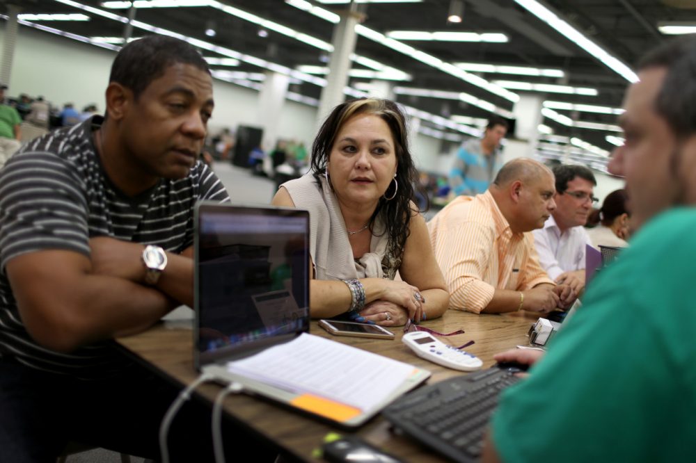 Jose Ramirez (left) and Mariana Silva speak with Yosmay Valdivia, an agent from Sunshine Life and Health Advisors, as they discuss plans available from the Affordable Care Act at a store setup in the Mall of the Americas on December 15, 2014 in Miami, Florida. (Joe Raedle/Getty Images)